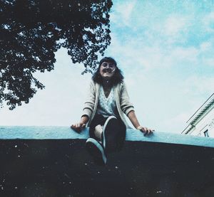 Portrait of woman sitting by sea against sky