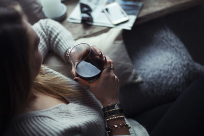 Young woman with glass of coffee relaxing on couch at home