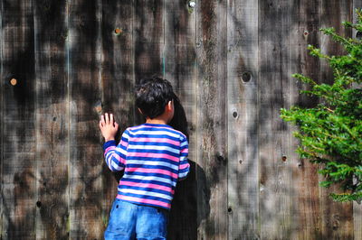 Child looking through wooden fence