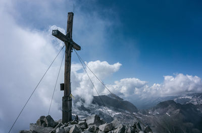 Low angle view of cross on mountain against sky