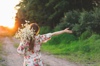 Portrait young beautiful woman with chamomile flowers at sunset.