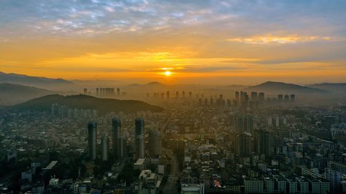 Aerial view of city against cloudy sky during sunset