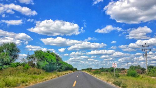 Road by landscape against blue sky