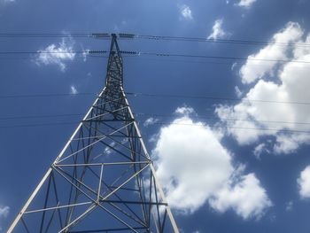 Low angle view of electricity pylon against blue sky