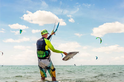 Man holding umbrella at beach against sky