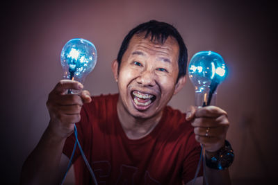 Portrait of smiling man holding illuminated light bulb