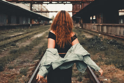 Rear view of woman standing on railroad track