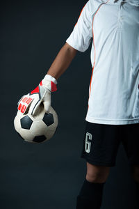 Low angle view of woman playing soccer ball against black background