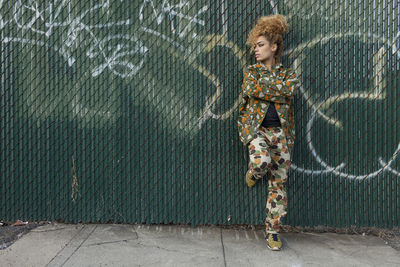 Portrait of man standing on sidewalk against wall