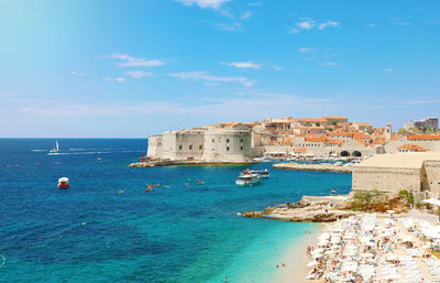 Scenic view of sea by buildings against sky