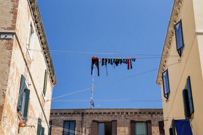 Low angle view of clothes drying on clothesline between buildings