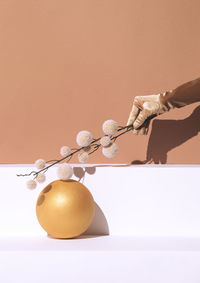 Autumn minimalistic scene hand in gold gloves holding decor brunch and geometry ball. seasonal fall 