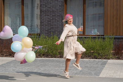 Woman with balloons while standing in city
