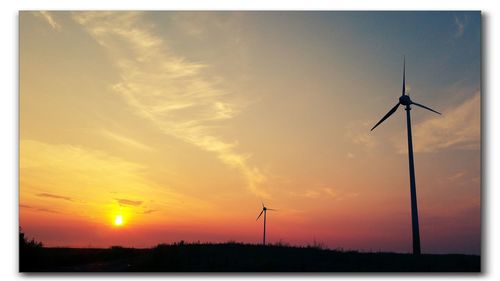 Silhouette windmill on field against sky during sunset