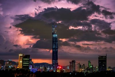 Illuminated buildings in city against sky during sunset