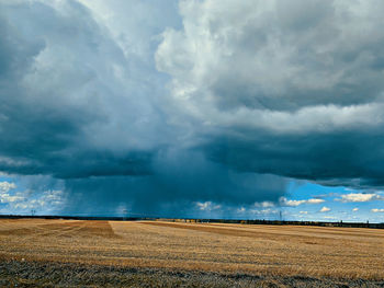 Scenic view of field against storm clouds