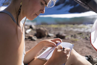 Close-up of woman holding hands while sitting on land