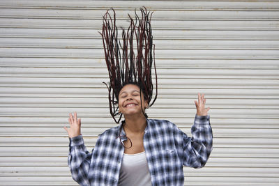 Portrait of smiling young woman standing against wall