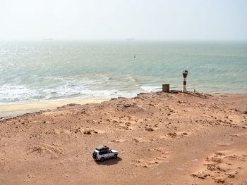 Off-road vehicle driving toward lifeguard hut overlooking sandy coastal beach