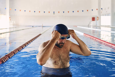 Male swimmer taking off swimming goggles and having break during active training