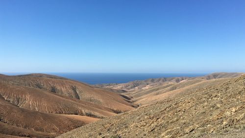 Scenic view of desert against clear blue sky