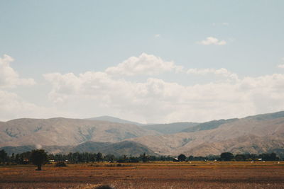 Scenic view of field and mountains against sky