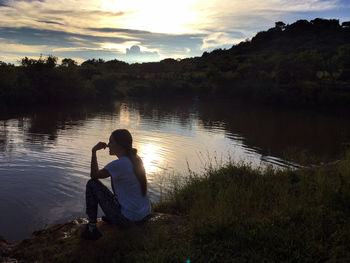 Man photographing lake against sky during sunset