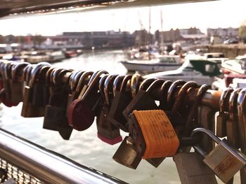 Close-up of padlocks hanging on railing by river in city