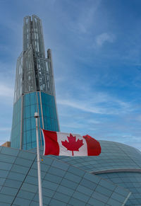 Low angle view of flag by building against sky