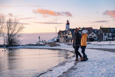 Rear view of man standing on snow against sky during sunset