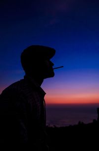 Artist standing against vibrant sunset on a beach.