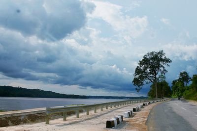 Scenic view of road by trees against sky