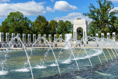 Water fountain in swimming pool against sky