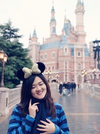 Portrait of smiling young woman holding building in city