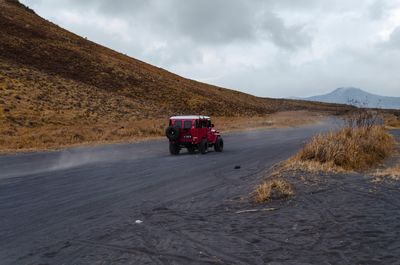 Car on road by land against sky