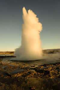 View of sun shining through clouds over water