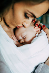 Mother carrying newborn son at home