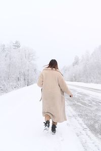 Rear view of woman walking on snow covered land