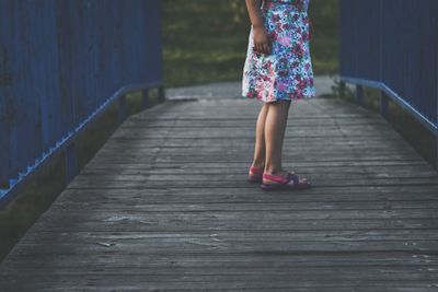 Low section of girl standing on footbridge