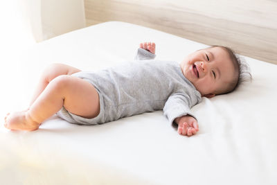 Portrait of cute smiling baby boy lying on bed at home
