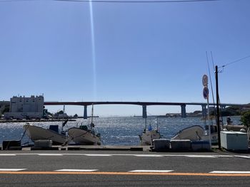 Road by sea against clear blue sky