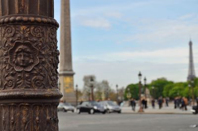 Close-up of carving on metallic pole with luxor obelisk and eiffel tower against sky