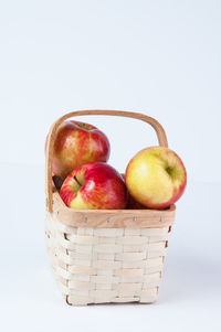 Close-up of apples in basket against white background