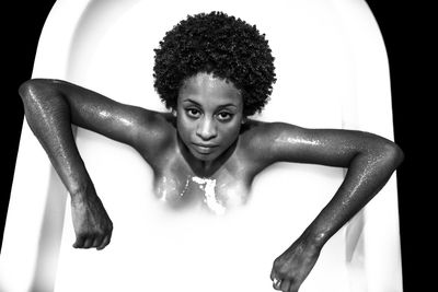 High angle portrait of woman in bathtub over black background