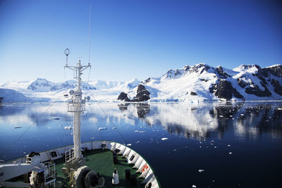 Cropped image of boat by iceberg against clear sky