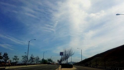 Cars on road against cloudy sky
