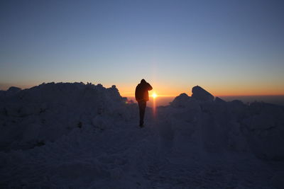Silhouette man walking on snow covered landscape
