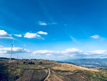 Windmills on landscape against blue sky