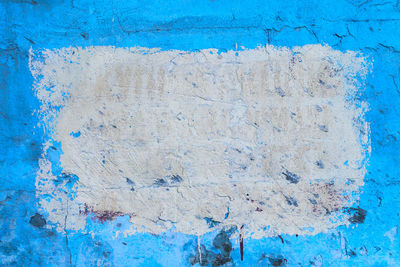 Full frame shot of weathered blue wall with white rectangle