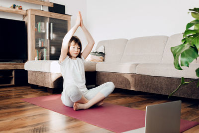 The girl sits on a sports mat and practices yoga. yoga for children and adults at home and online. 